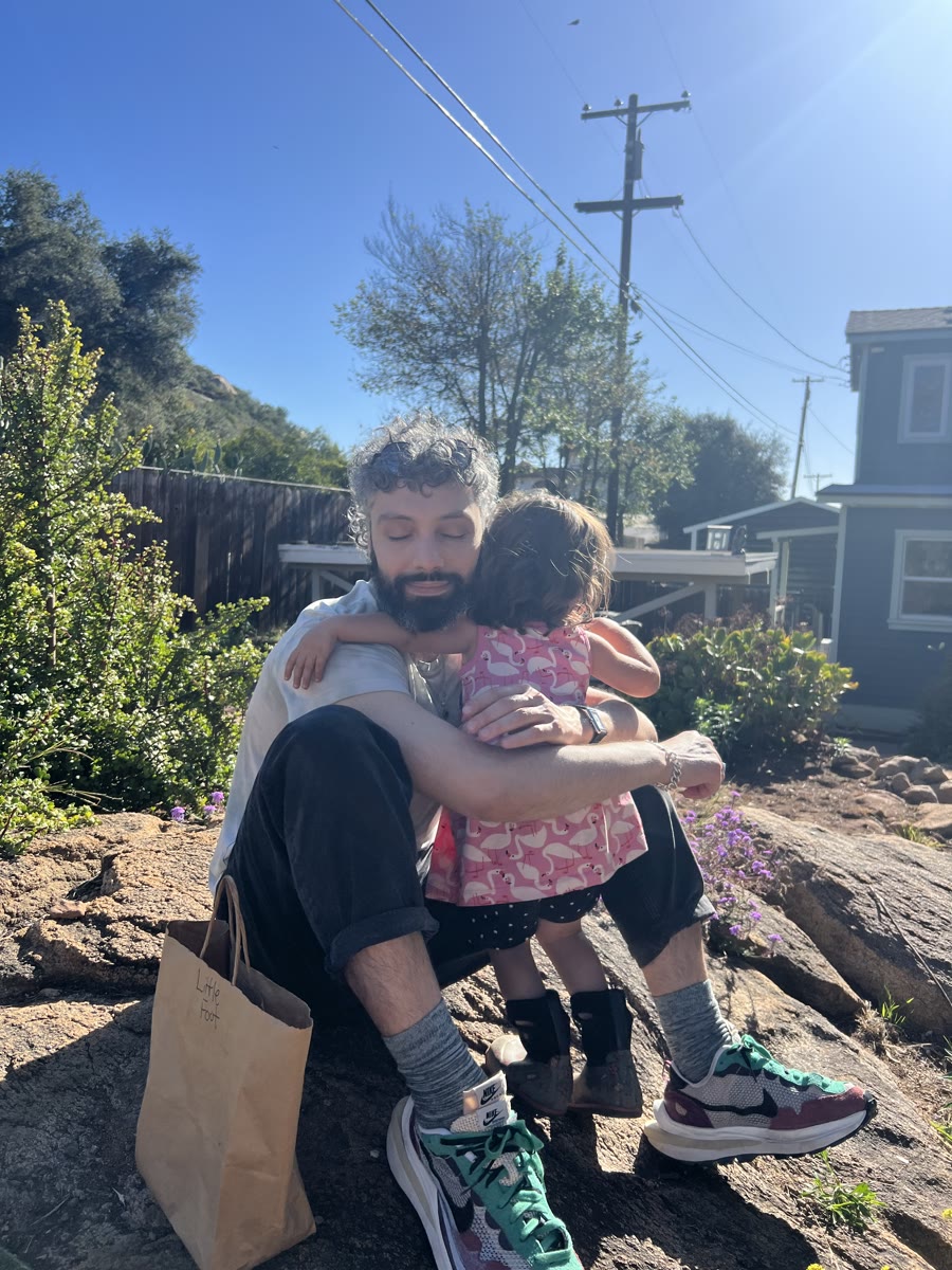 Lance sitting on a sunlit rock, hugging his niece